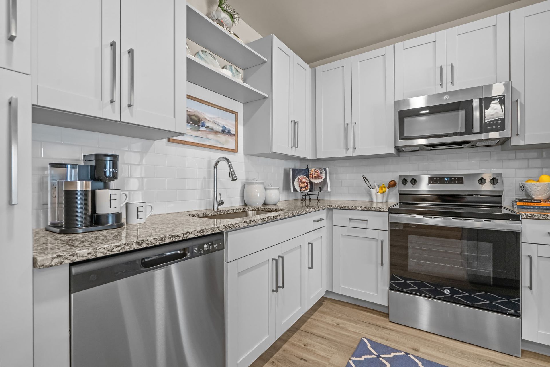 Contemporary white kitchen with granite counters, stainless steel appliances, and subway tile backsplash.