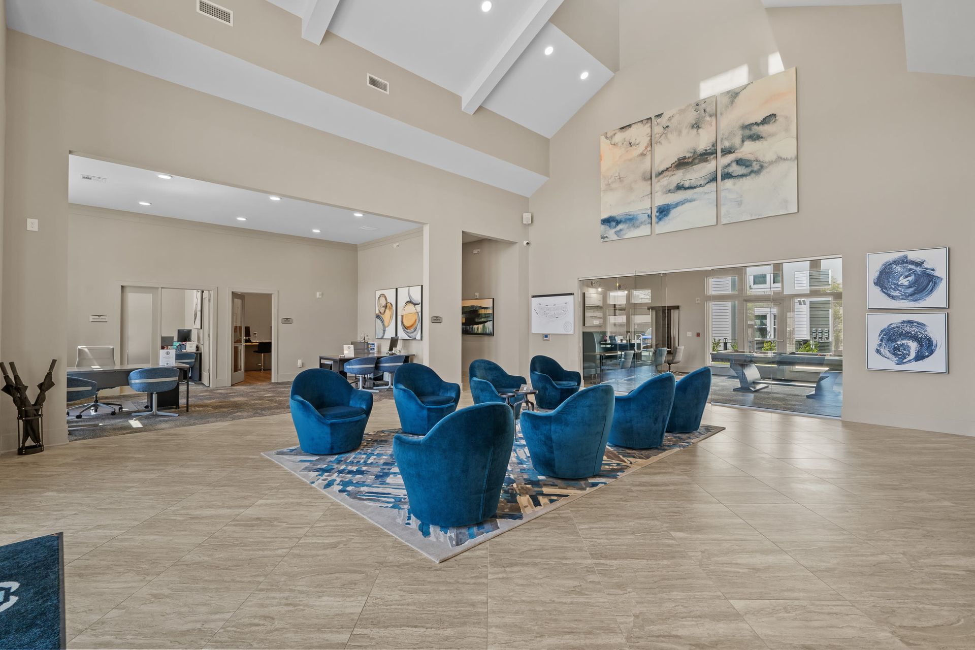 Spacious apartment community lobby with blue lounge chairs, neutral walls, and wall art.