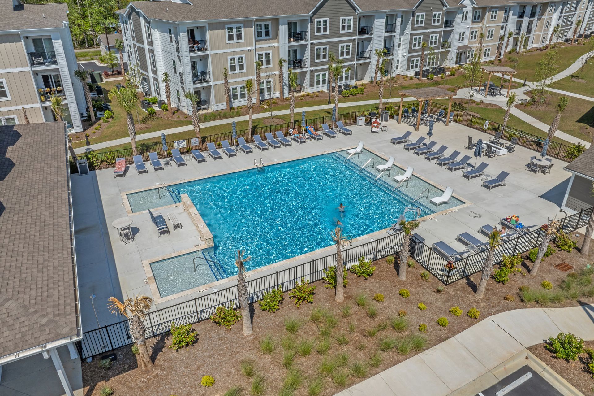 Aerial view of a community swimming pool surrounded by lounge chairs and apartment buildings.