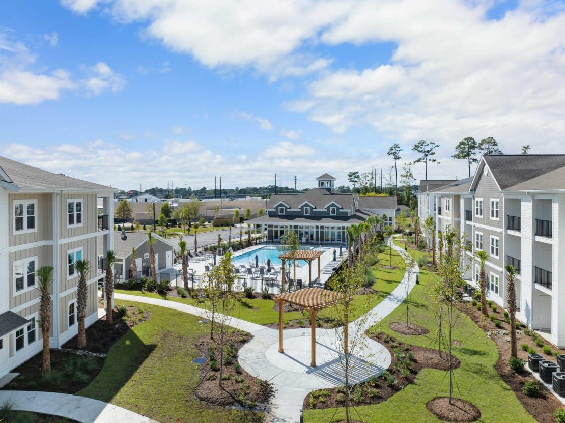 Aerial view of a modern apartment community with a central pool and surrounding buildings.