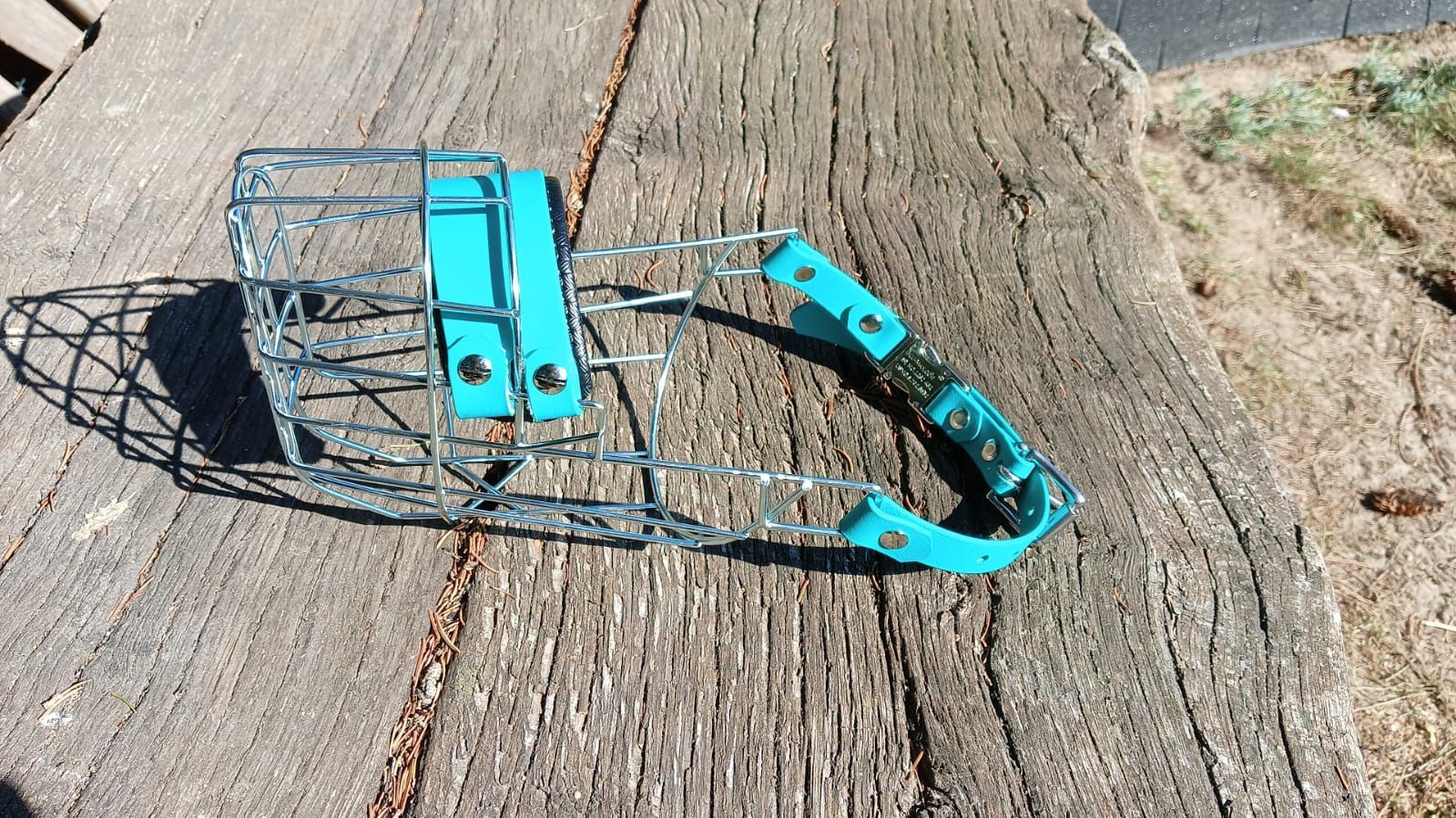 Ein blauer Hundemaulkorb liegt auf einer Holzoberfläche.
