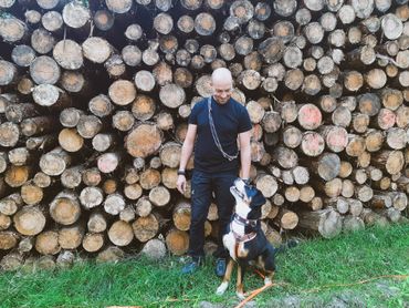 Pfotenerlebnis Mann mit Hund am Holzstapel