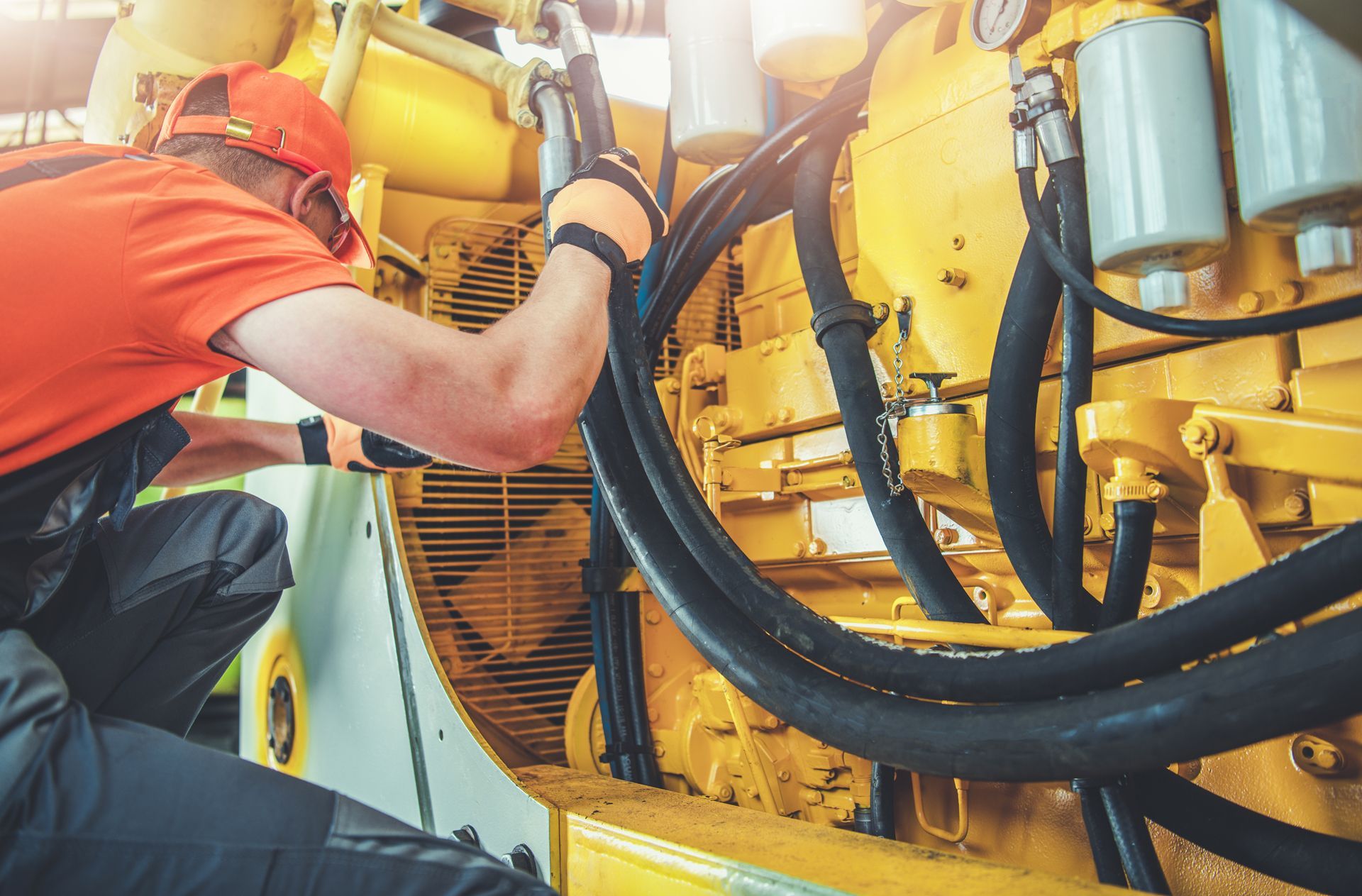 A Man is Working on a Large Yellow Engine