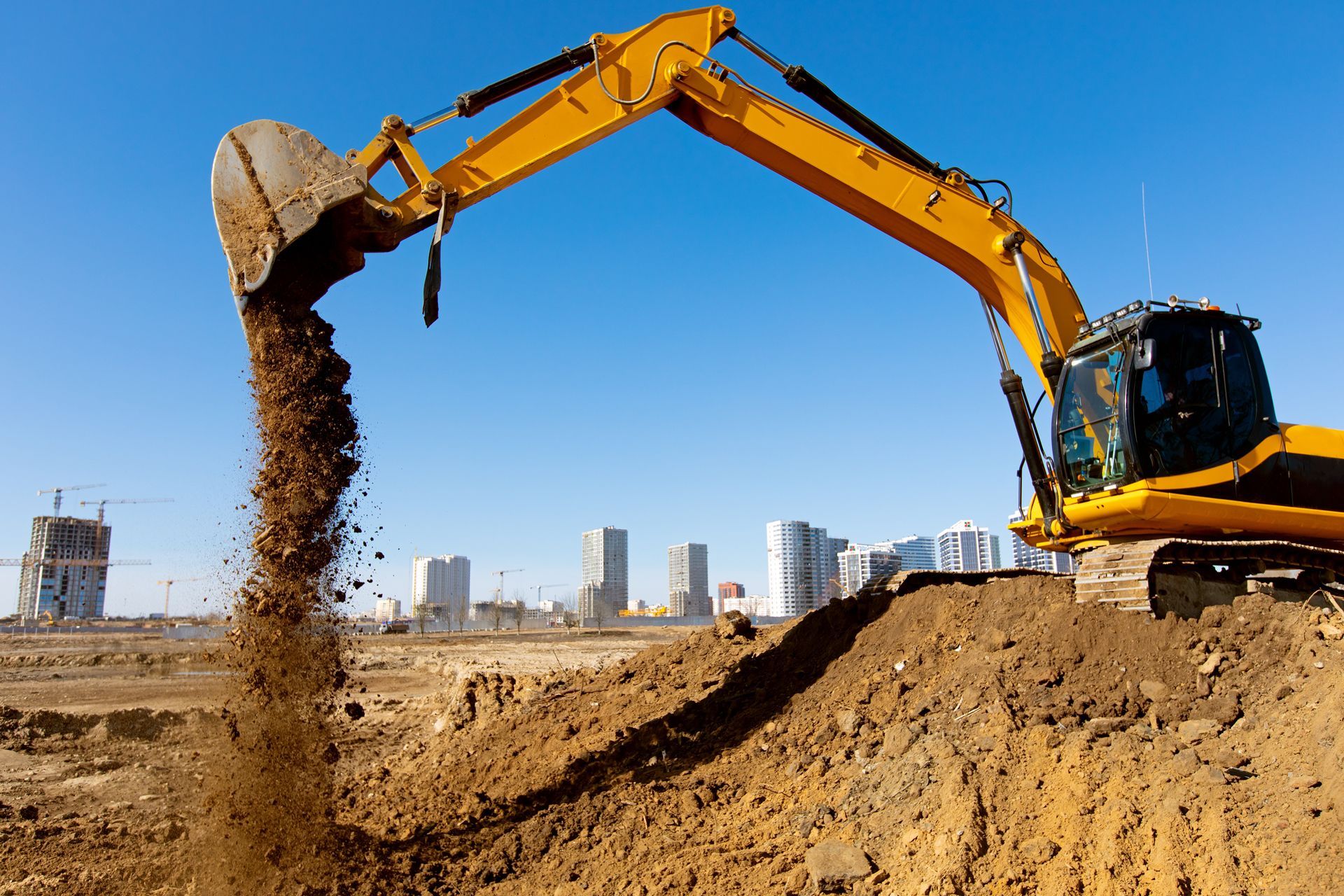 A yellow excavator is digging a hole in a construction site.