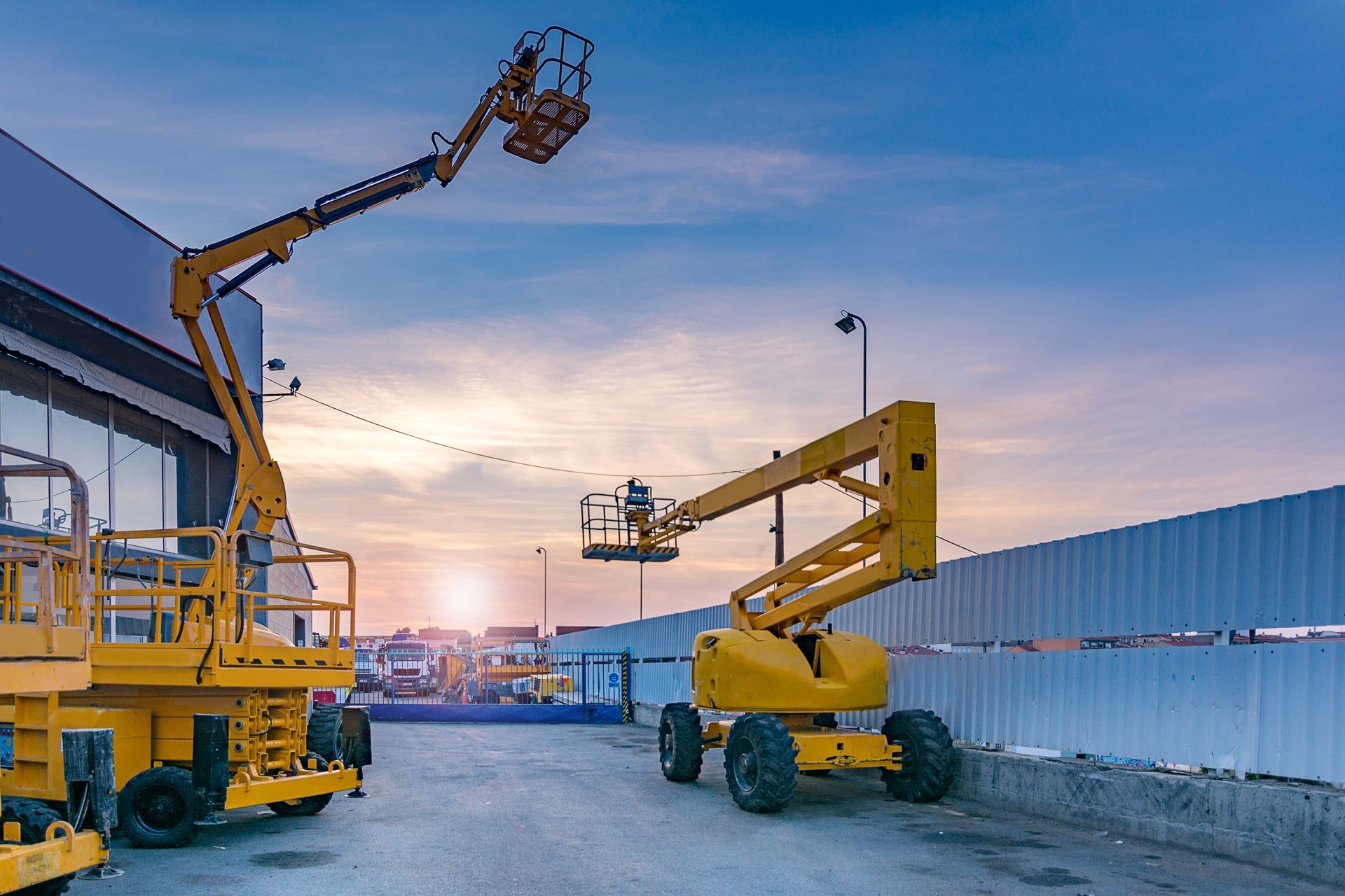 Two Yellow Aerial Lifts Are Parked in Front of a Building