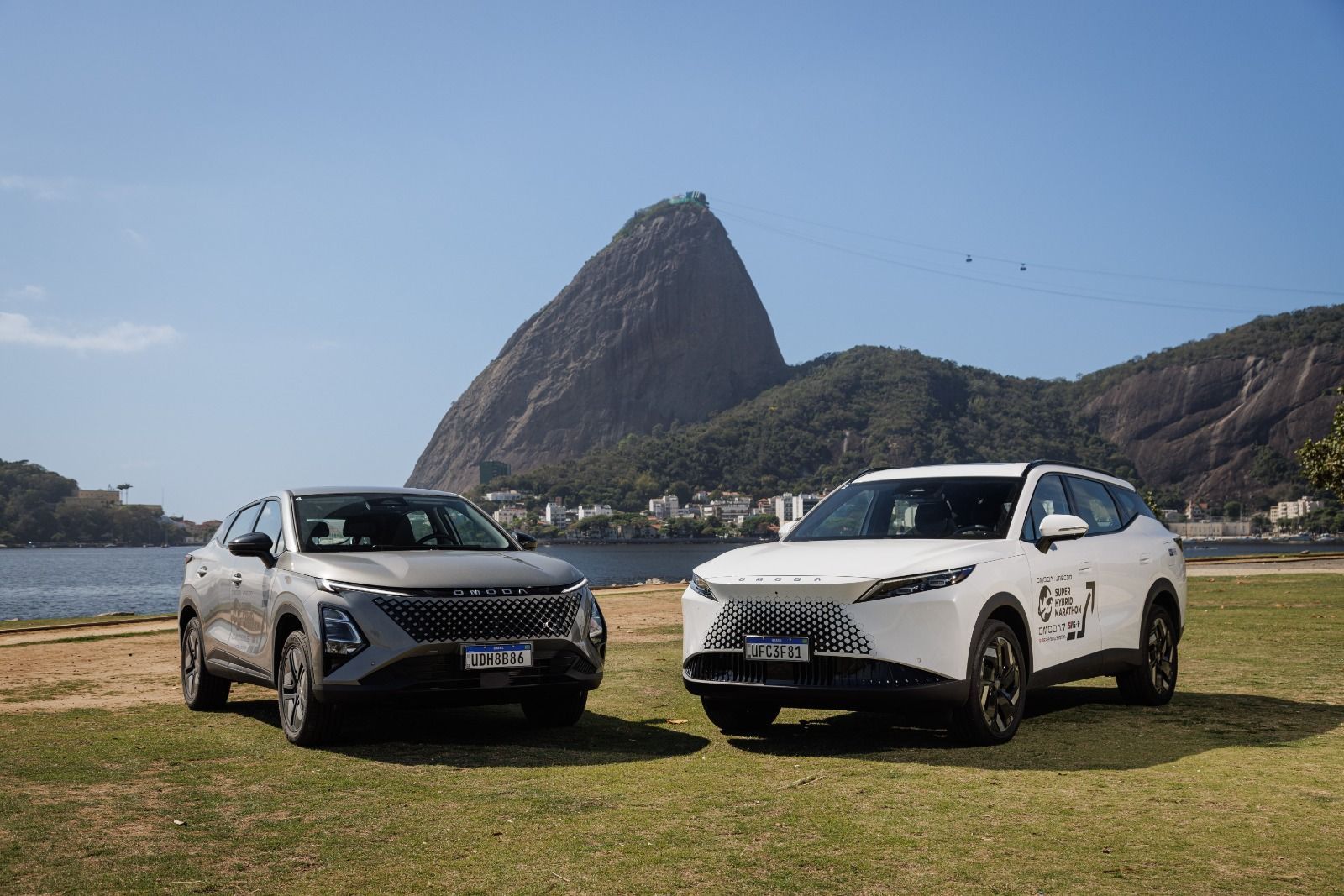 Two SUVs parked on grass with a rocky mountain in the background