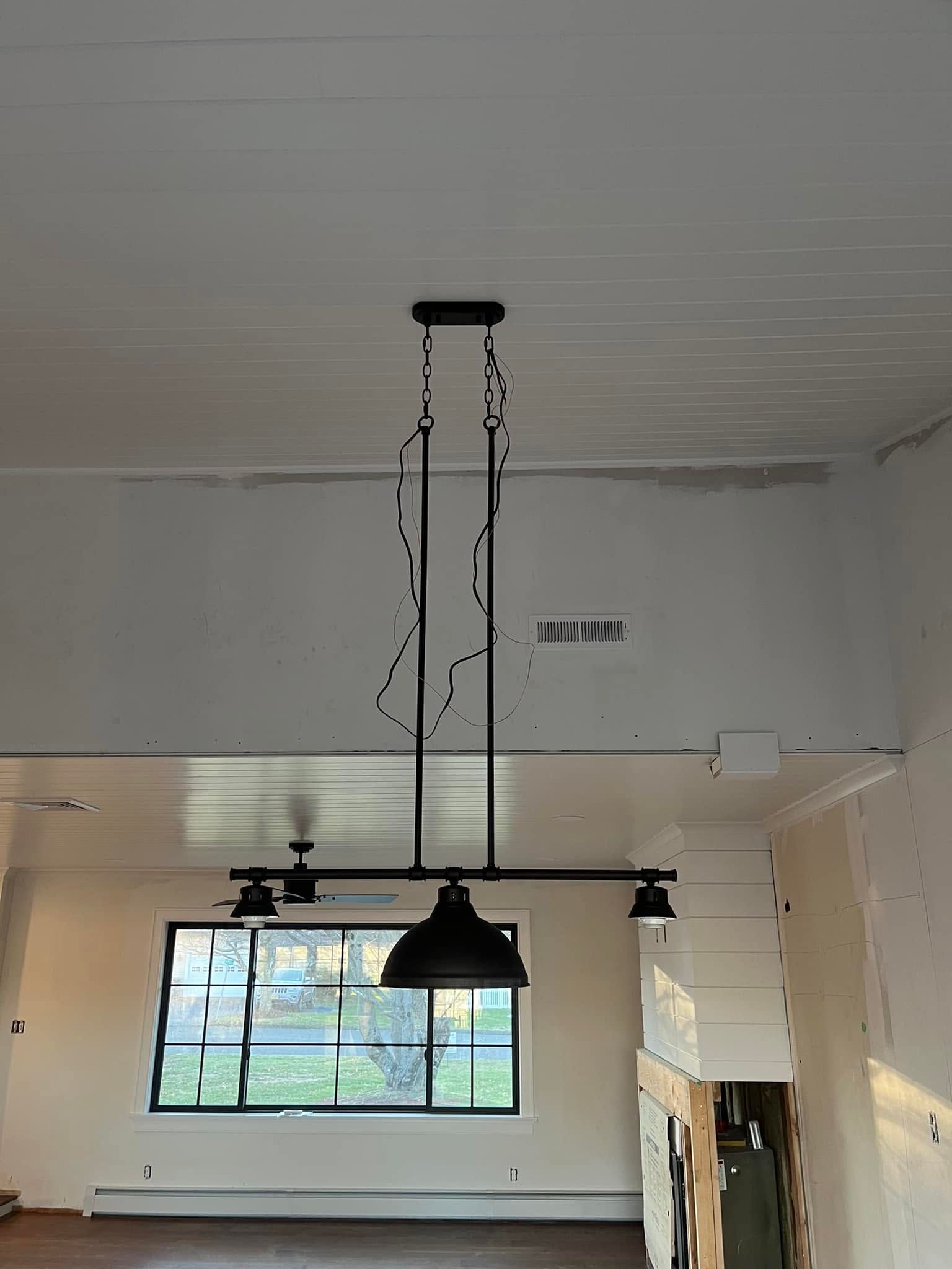 High-ceiling room with a hanging black light fixture above a large window