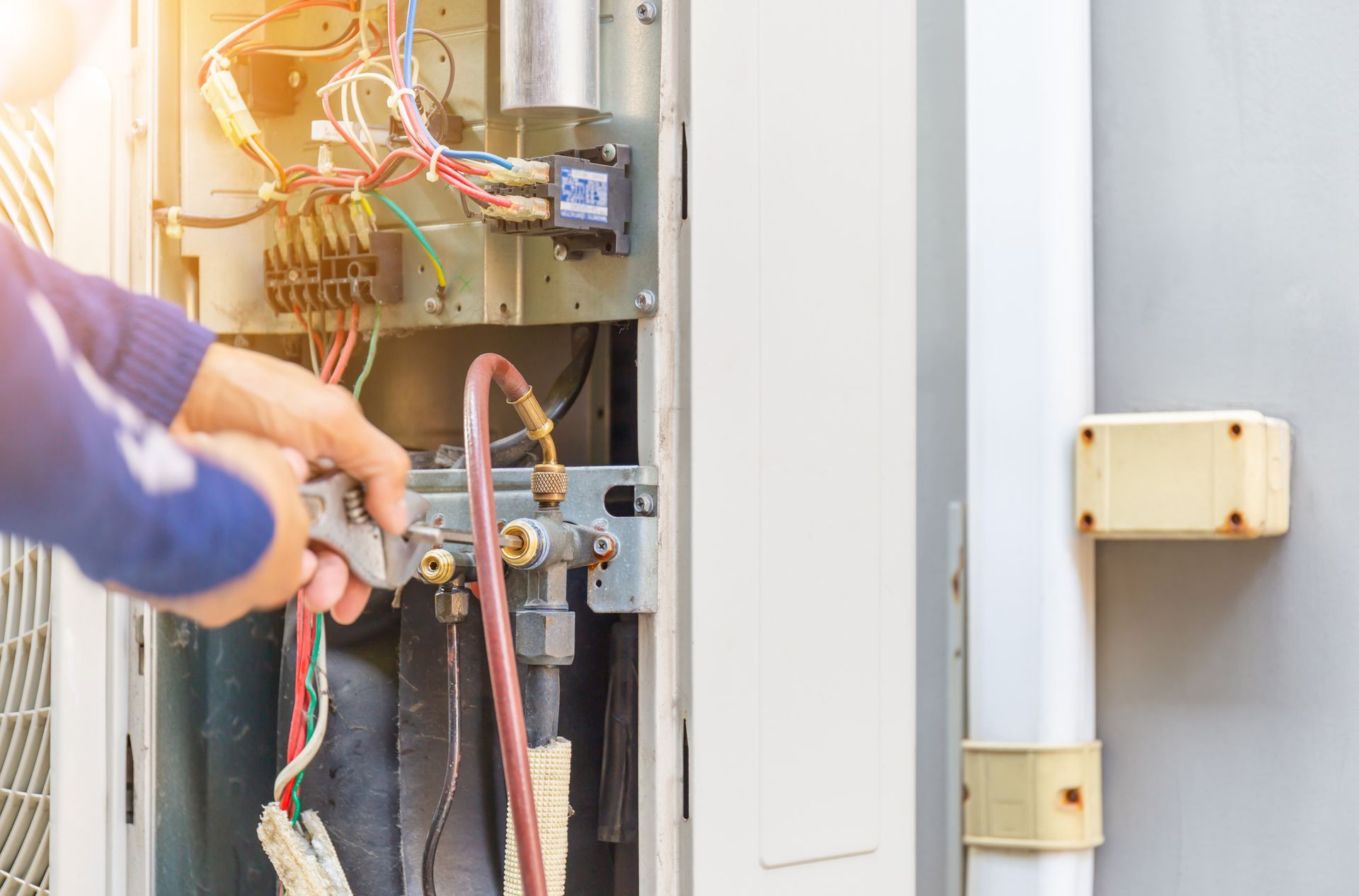 Technician repairing exposed electrical wiring inside an outdoor utility panel