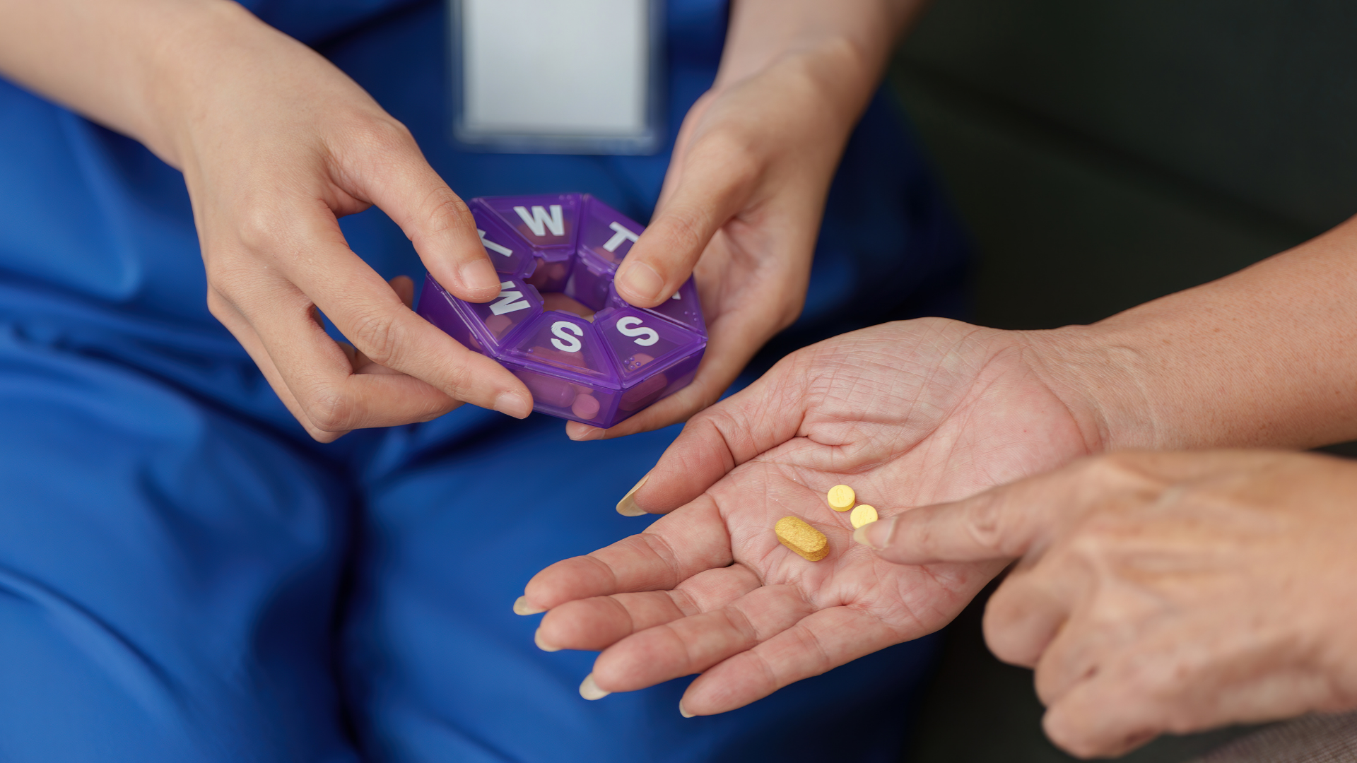 Hands holding a purple pill organizer and yellow pills above an open palm.