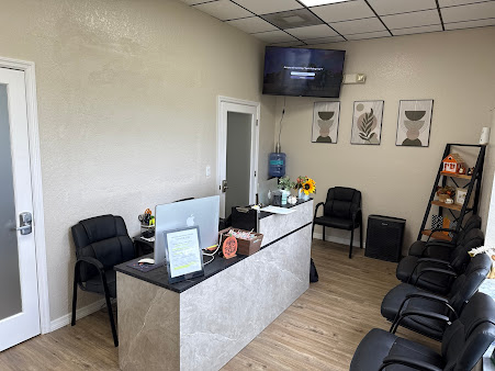Small waiting room with black chairs, reception desk, wall TV, and framed artwork.