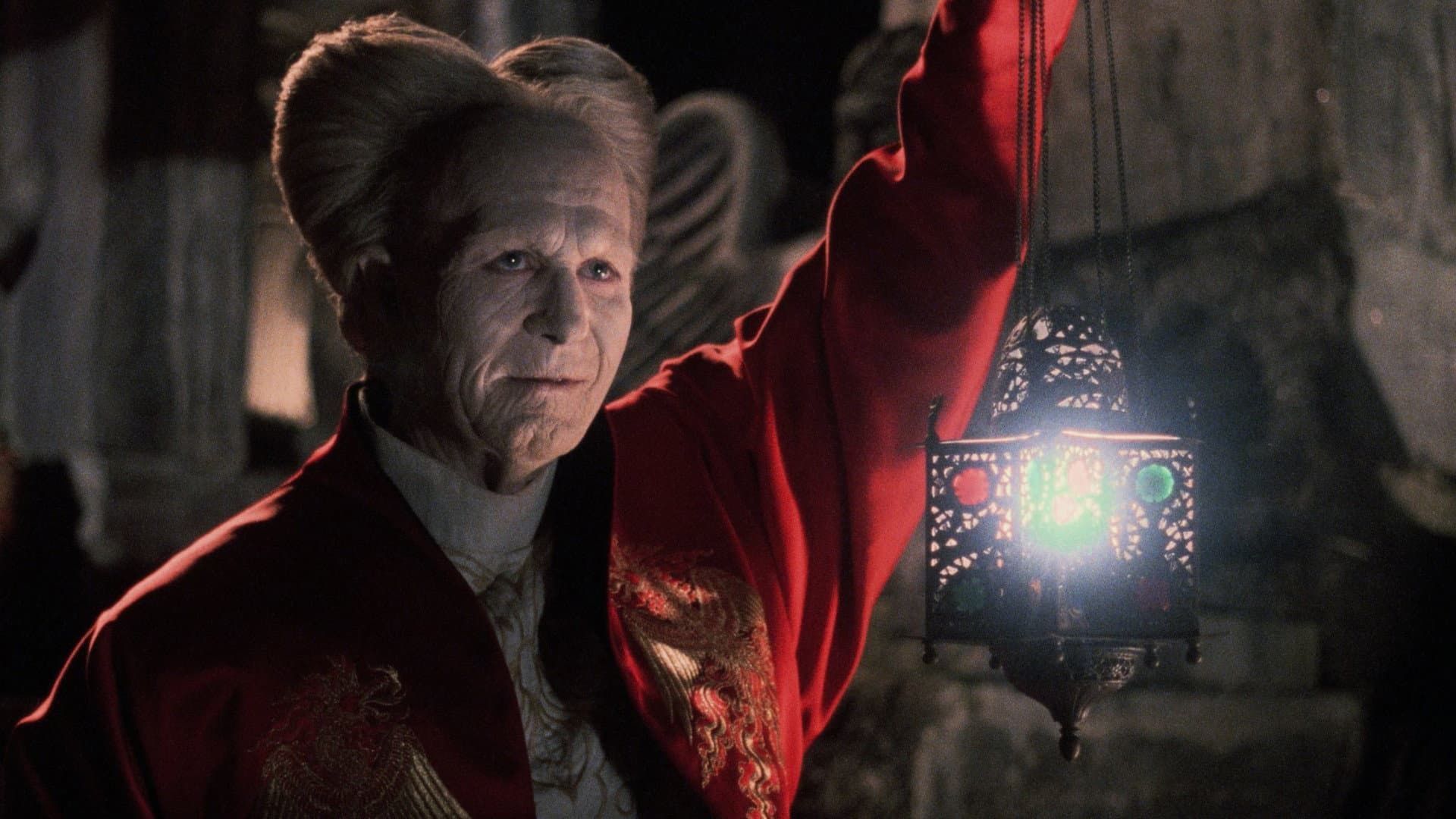 A person in a red coat holds up a glowing lantern in a dark cave-like setting.