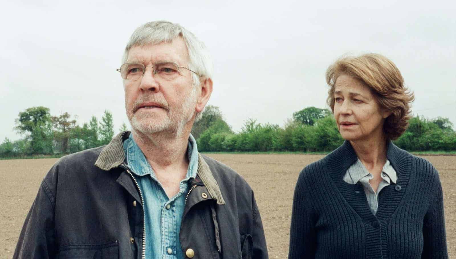 An older man and woman stand in a field