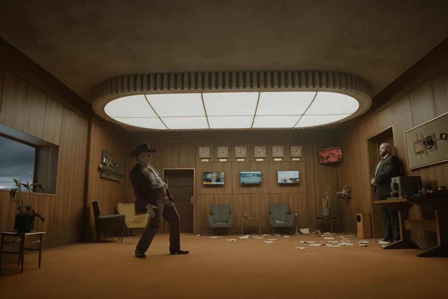 Retro wood-paneled room with a person dancing under a curved skylight, screens on the far wall.