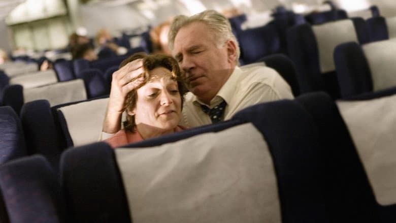 Passengers resting in airplane seats, one leaning back with eyes closed while another supports their head