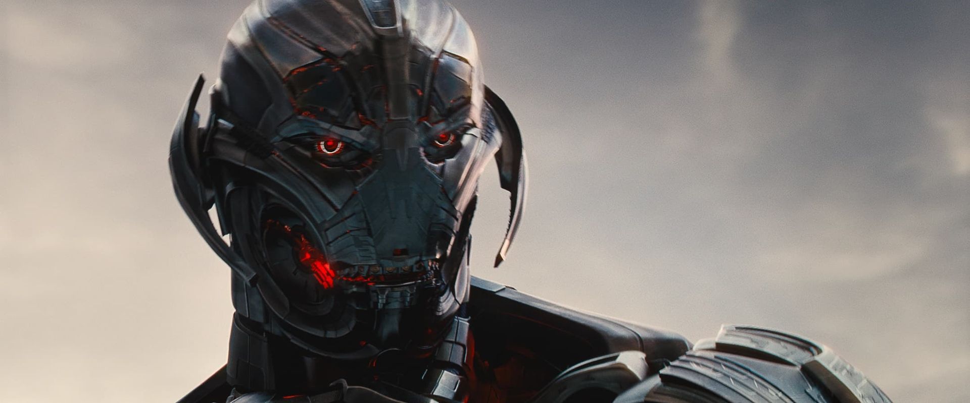 Menacing black robot head with glowing red eyes against a cloudy sky