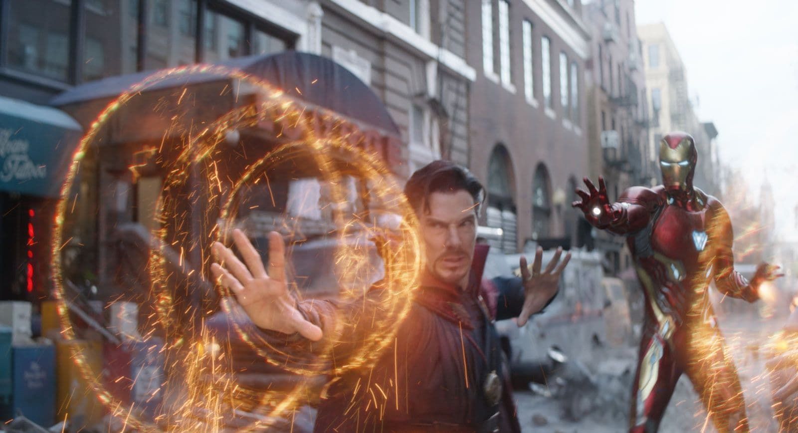 Doctor Strange and Iron Man battle amid glowing orange magic on a city street.