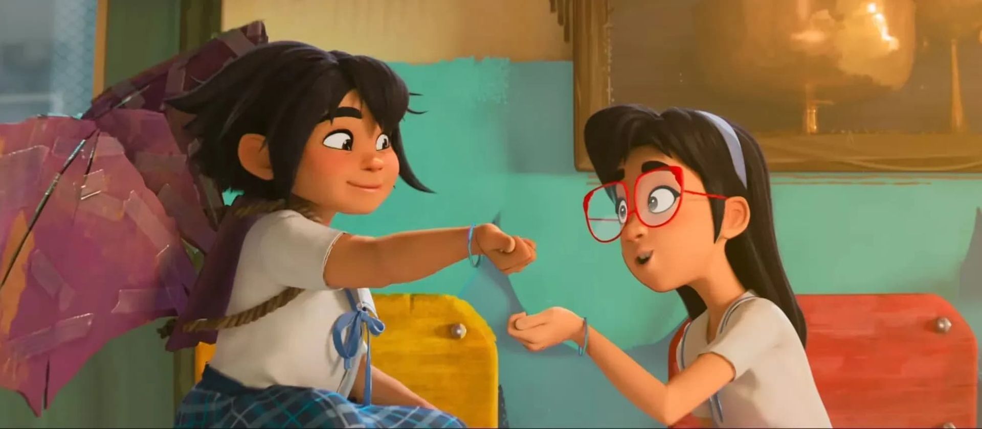 Two girls on colorful beds exchanging a fist bump in a cozy bedroom.
