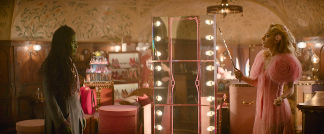 Two women face each other in a softly lit boutique with mirrors, string lights, and clothing racks.