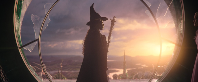 Silhouetted wizard in a circular window at sunset, overlooking a glowing sky and distant landscape
