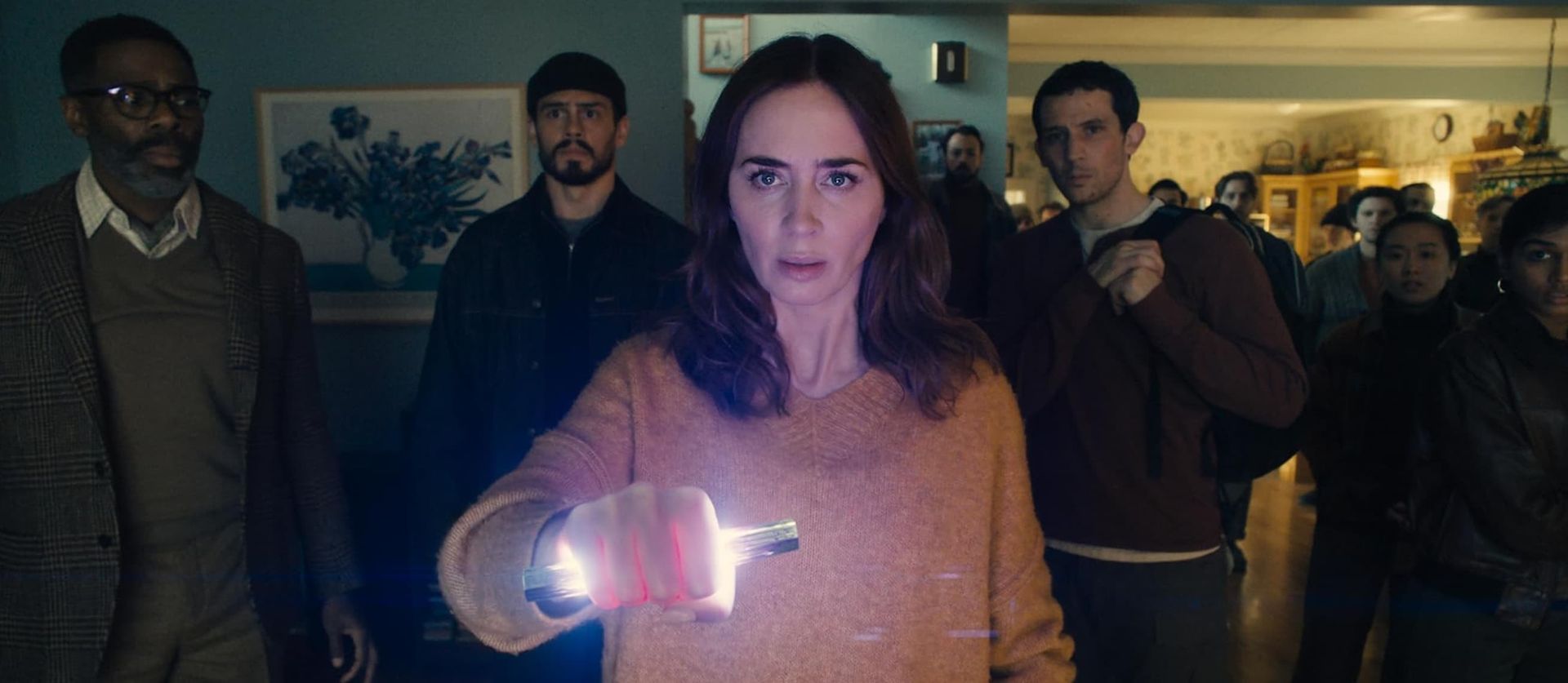 Woman holding a glowing object in a dimly lit room, with several people standing behind her
