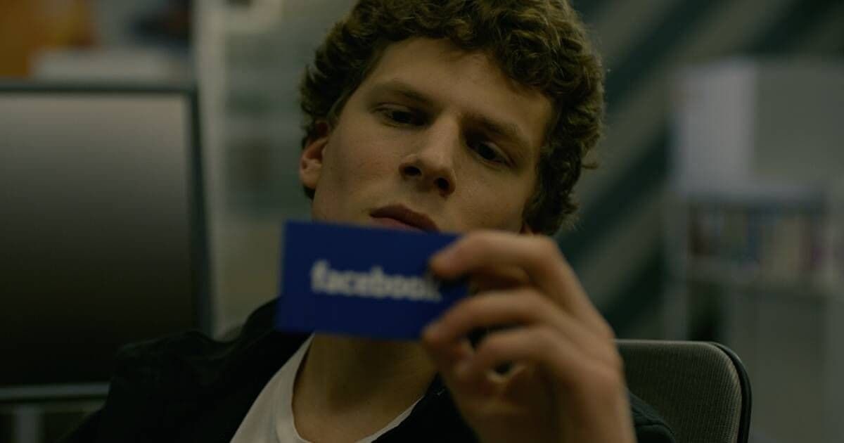 Person holds up a blue Facebook card indoors, looking at the camera.