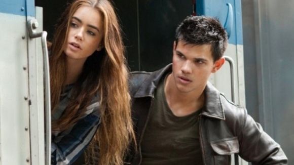 Lily Collins and Taylor Lautner looking out of a train door