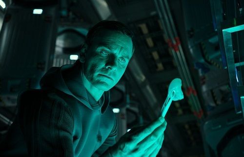 Man in a blue-lit space setting examines a glowing object with a serious expression.