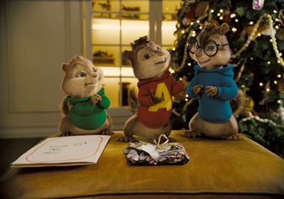 The Chipmunks (Alvin, Simon, Theodore) by a gift and Christmas tree.