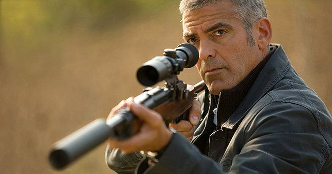 George Clooney aiming a rifle with a scope, outdoors, focused expression, gray hair.