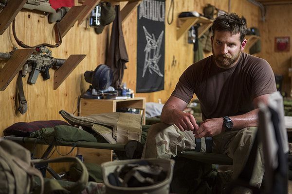 Bradley Cooper in a military setting, looking somber.