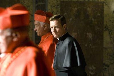 A priest looks concerned, walking beside red-robed cardinals in a church.