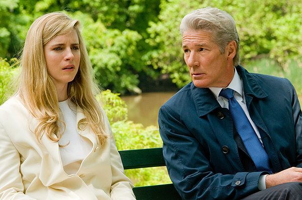 Blonde woman and older man on a bench by water; she looks worried, he looks concerned.