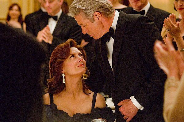 Richard Gere and Susan Sarandon, formal event. Gere leans towards Sarandon, attendees applaud.