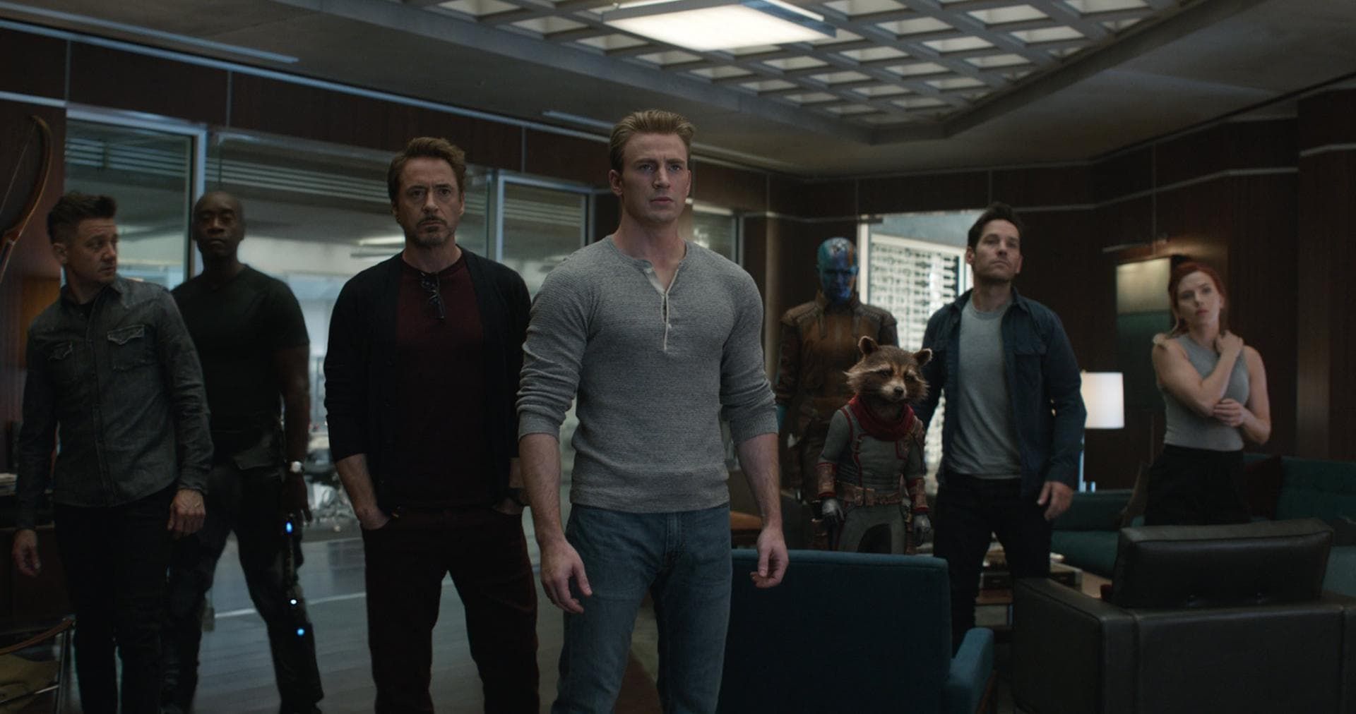 Superhero team standing in a dark control room, facing forward with serious expressions.