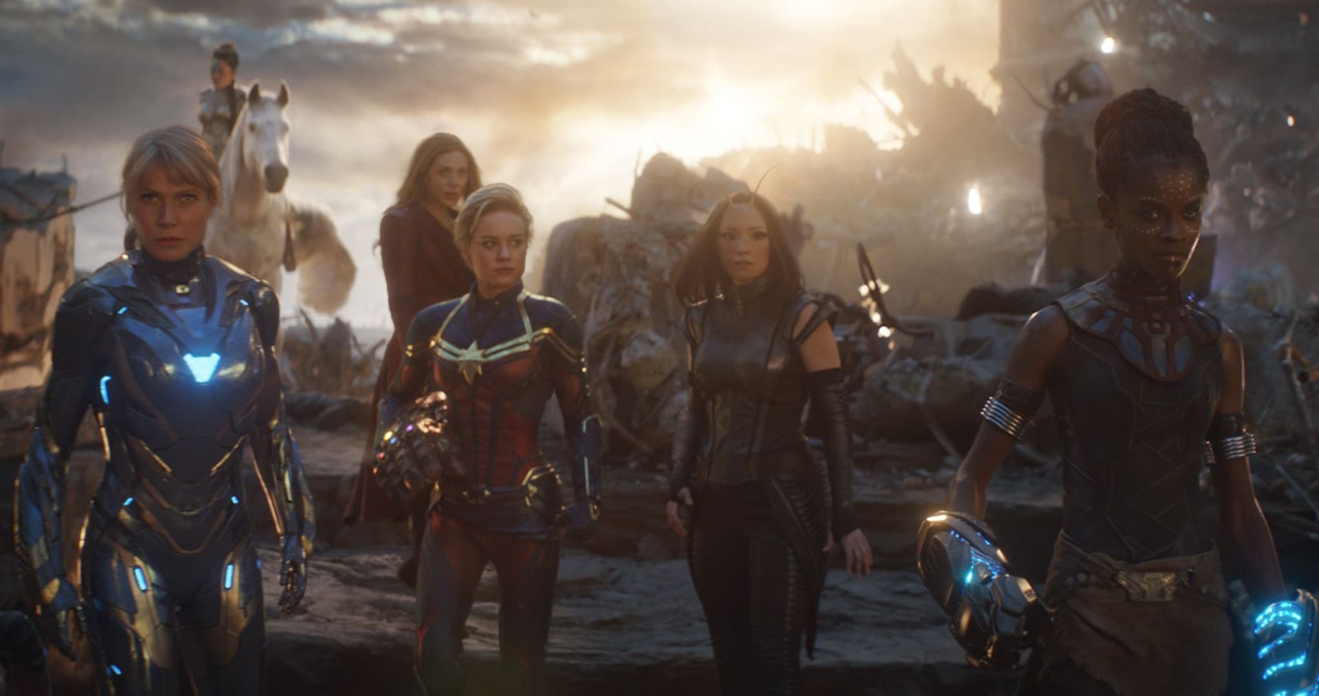 Superhero team stands in battle gear on a smoky battlefield at sunset