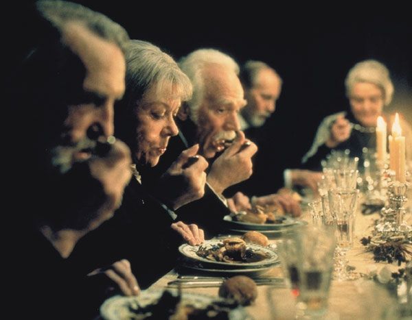 People at a candlelit formal dinner, eating from plates.