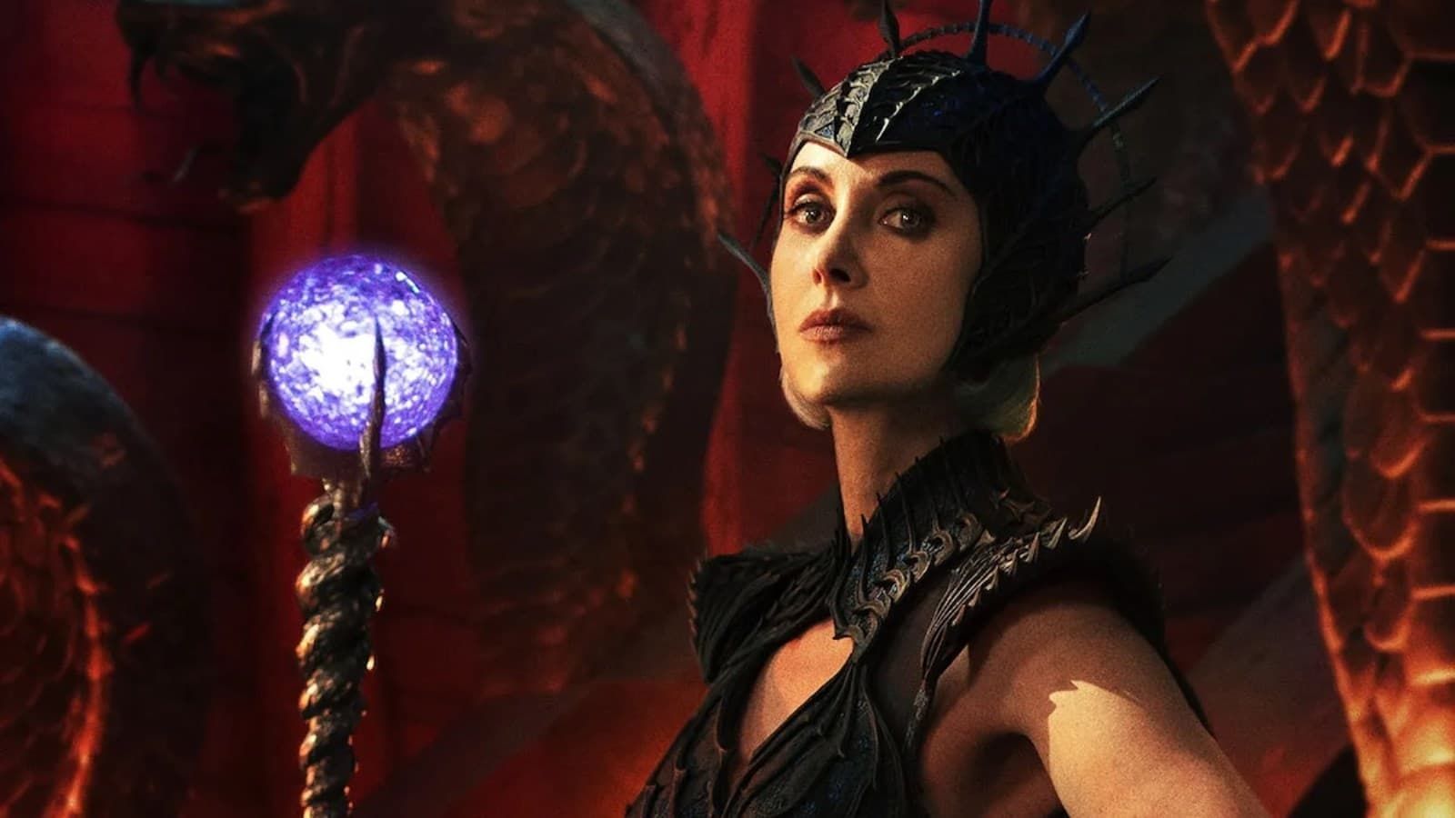 Dark-clad sorceress holding a glowing purple staff in a red, cavernous chamber