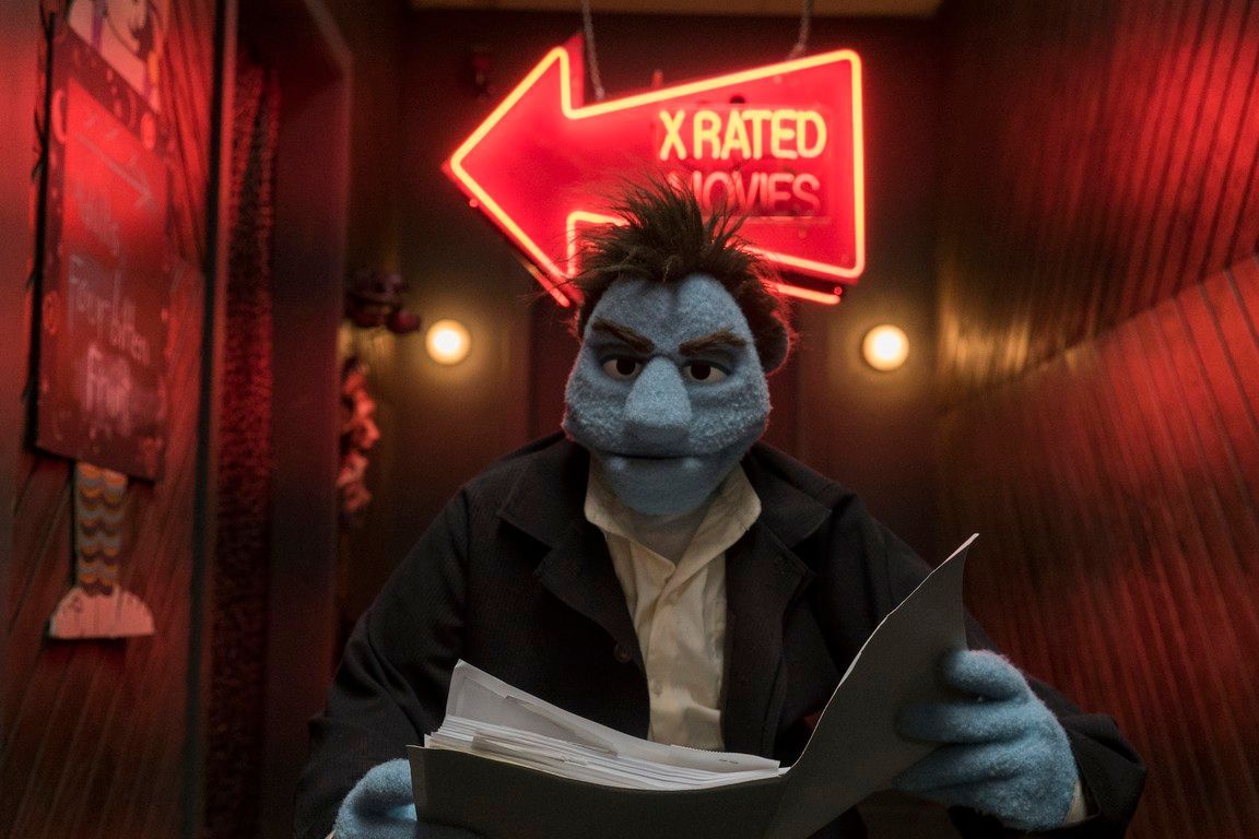 Blue puppet holding papers under an