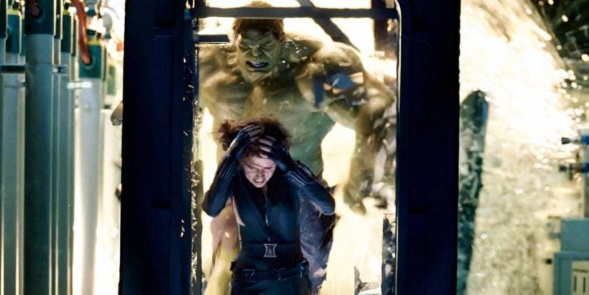 Man crouching in a sci-fi corridor as a giant creature looms behind him in a burst of light