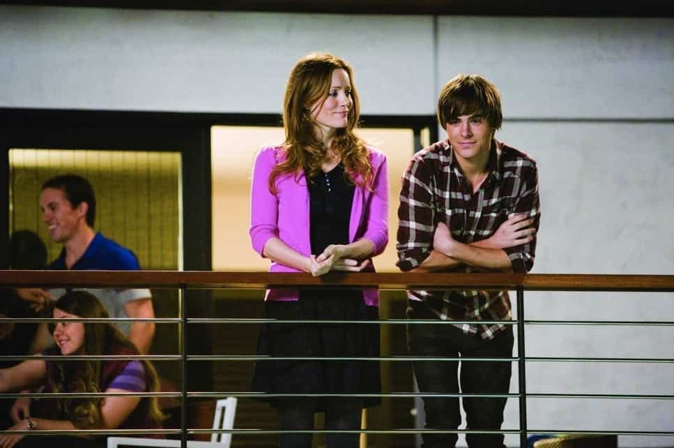 Woman and man, smiling, stand on a balcony