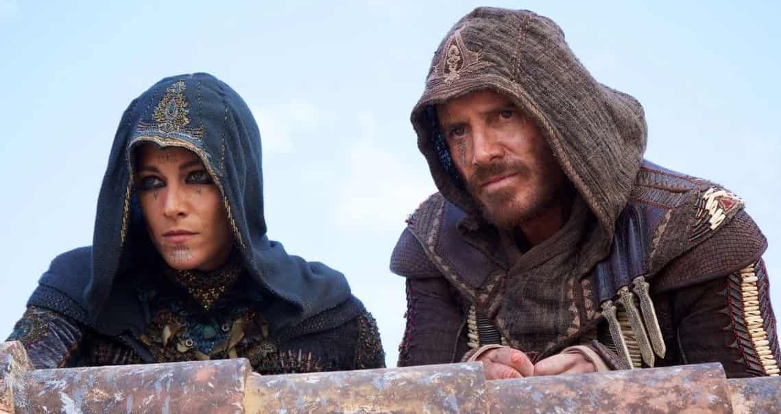 Woman and man in hooded robes, looking focused. Rooftop setting, blue sky.