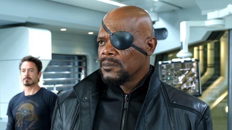 Two men in a futuristic interior, one wearing an eyepatch and black jacket in the foreground.