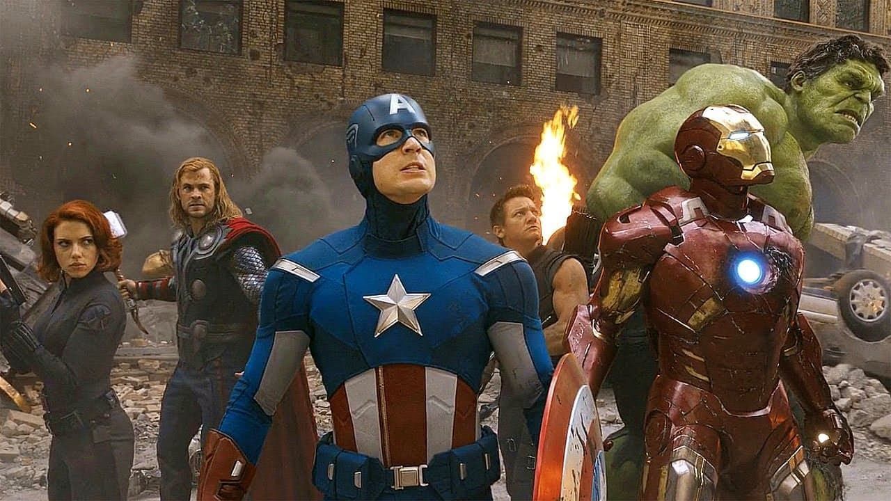 Superhero team standing amid rubble, with Captain America, Iron Man, Hulk, Thor and others ready for battle