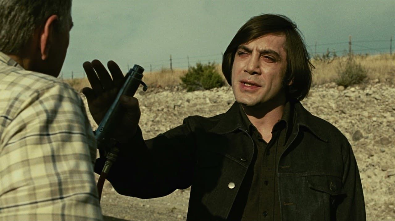 Two men face off in a dry field; one raises a hand while holding a shotgun.