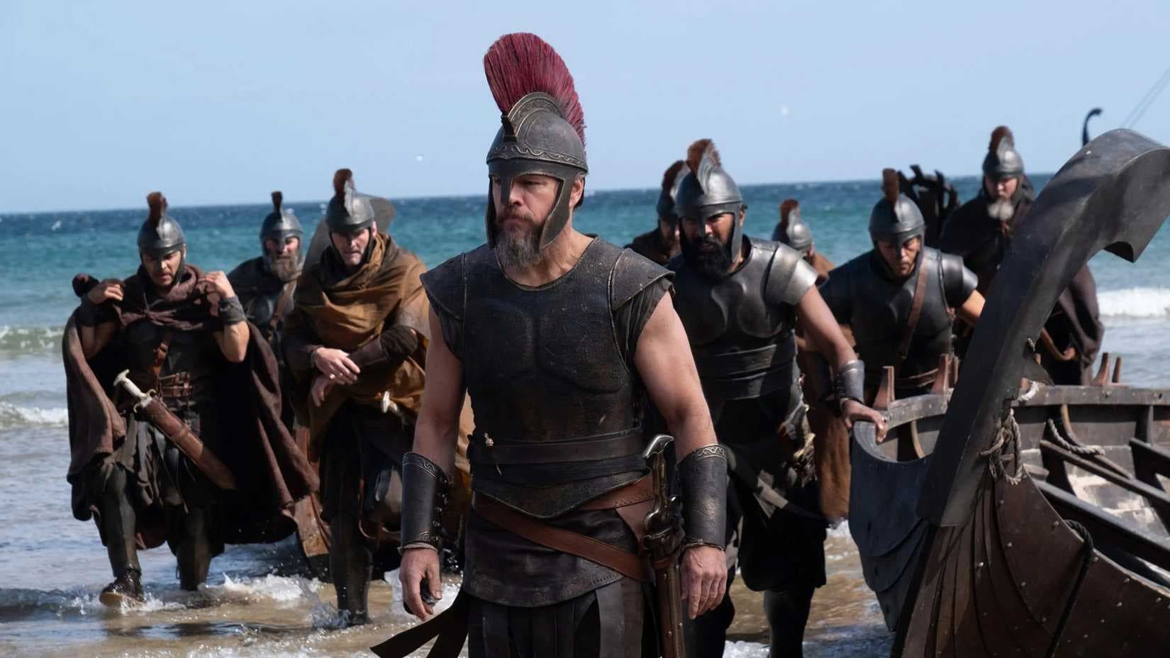 Armored warriors with shields and spears wade ashore from a longship on a rocky beach under a blue sky