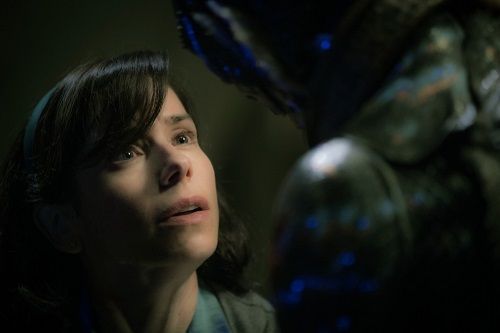 Sally Hawkins looks up at a large, green, scaly creature in a dark, aquatic environment.
