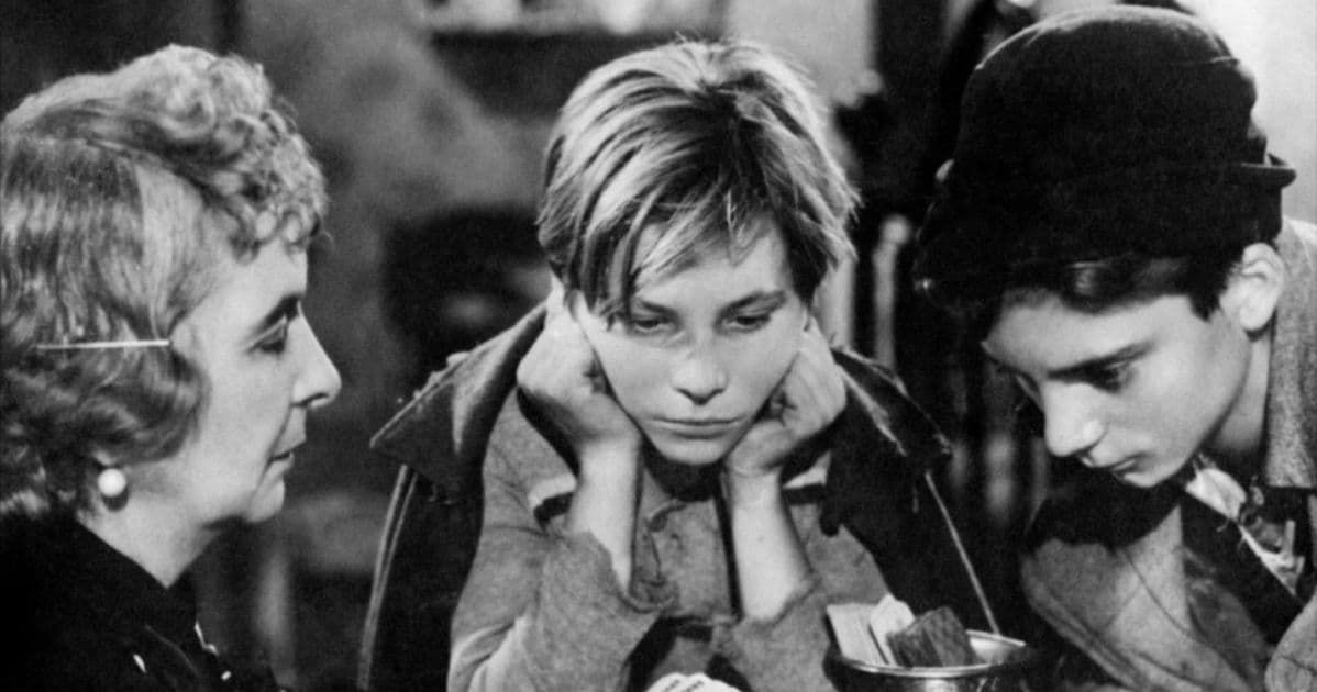 Three people leaning over a table, looking down in a black-and-white scene