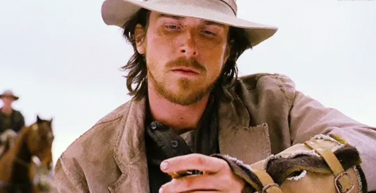 Man in cowboy hat looking distressed in desert setting.
