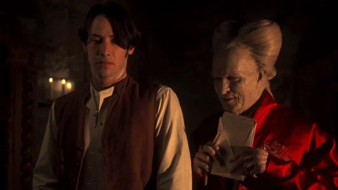 Two people in dim candlelight, one reading a note while the other looks on seriously.