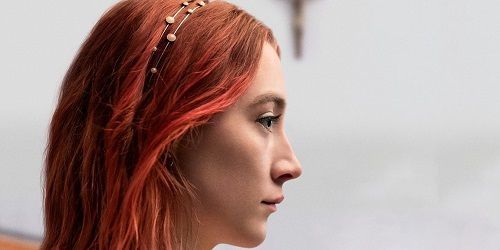 Woman with red hair and headband looks pensively to the right.